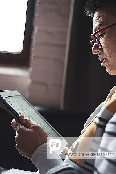 Nahaufnahme Seitenporträt einer asiatischen Frau mit Brille  die ein Arbeitsblatt liest