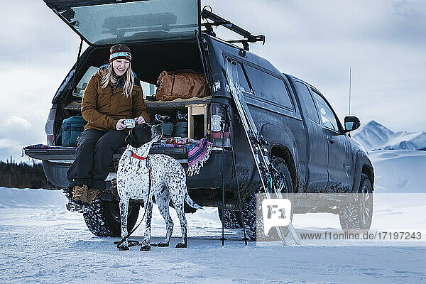 Glückliche Frau mit Hund im Geländewagen im Winter