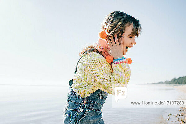 young girl laughing whilst playing at the beach in the sunshine