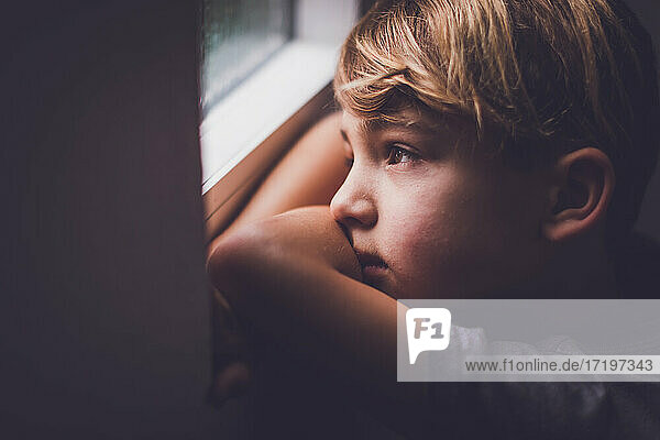 Boy with hazel eyes looking out the window.