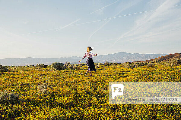 Fröhliche junge Frau tanzt in der Wüste Blumenfeld