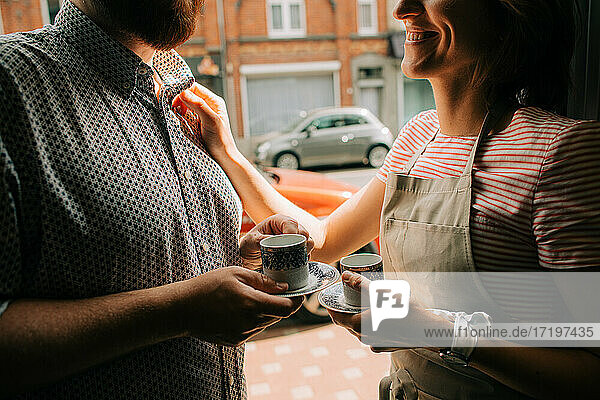 Junges Paar mit Kaffeebechern  das sich auf der Straße anlächelt