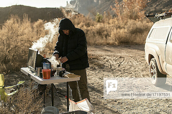 Mann bereitet Kaffee auf einem Campingkocher zu  während er im Urlaub den Canyonlands National Park erkundet