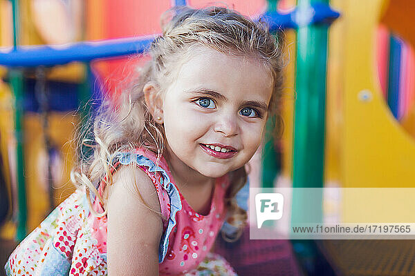 Preschooler girl looking at camera while playing at a playground.
