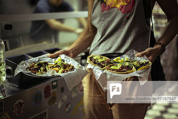 Gesundes mexikanisches Taco-Straßenessen  gehalten von starken gesunden Touristen