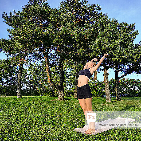Female yogi leaning backwards with arms up while standing straight