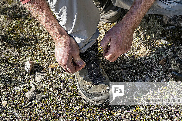 Mann beim Binden von Schnürsenkeln beim Wandern auf dem Berg Sant Llorenc del Munt i l'Obac in Katalonien  Spanien