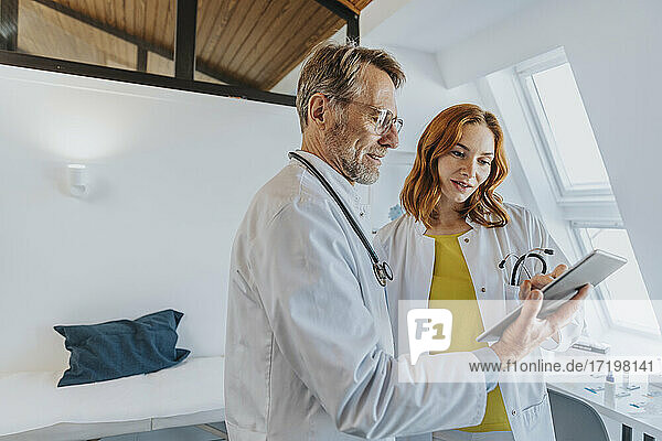 Männlicher Mitarbeiter arbeitet mit einem Arzt über ein digitales Tablet in einer Klinik
