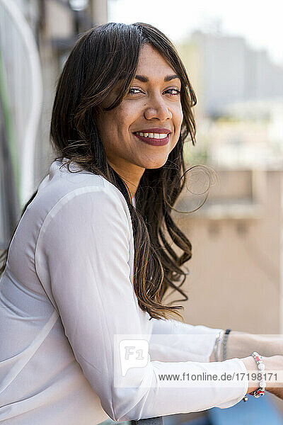 Schöne lächelnde Geschäftsfrau auf dem Balkon im Büro