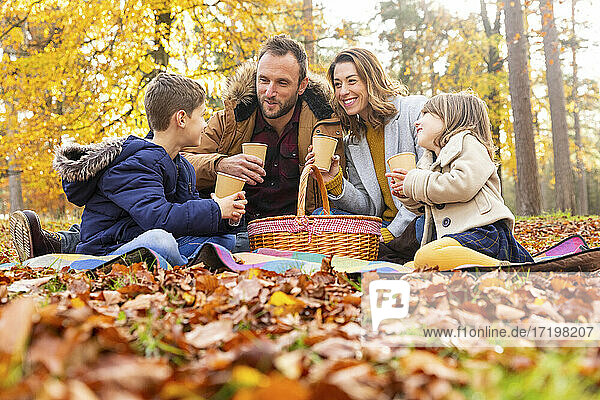 Lächelnde Familie beim gemeinsamen Kaffeetrinken im Wald