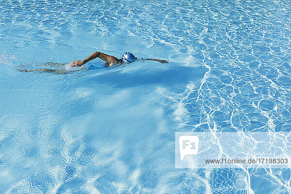 Frau schwimmt im klaren blauen Schwimmbad