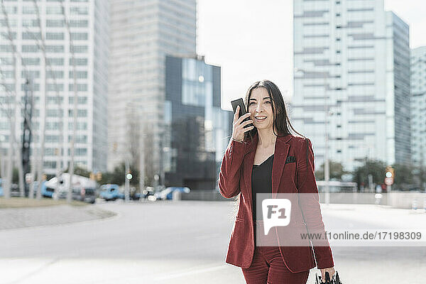 Geschäftsfrau  die beim Gehen in der Stadt mit ihrem Smartphone telefoniert