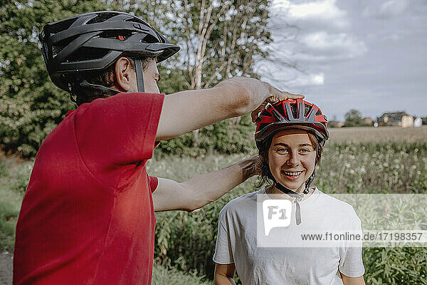 Father helping daughter wearing cycling helmet