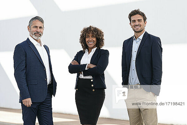Confident entrepreneurs smiling while standing against white wall