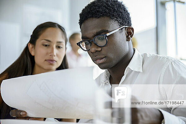 Ein männlicher und eine weibliche Architektin arbeiten im Sitzungssaal an einem Bauplan
