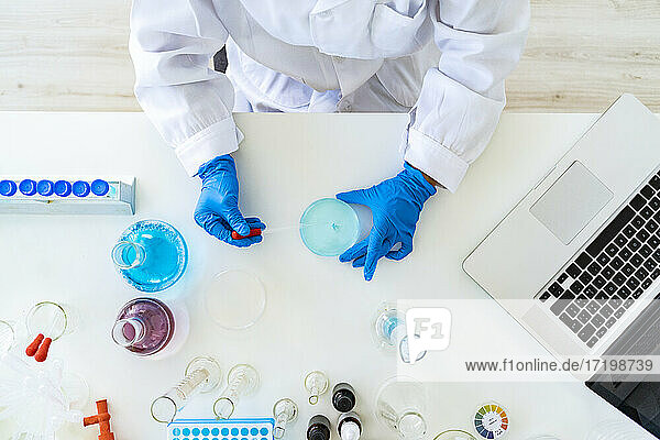 Die Hände einer Forscherin mischen eine Lösung durch eine Pipette im Chemielabor
