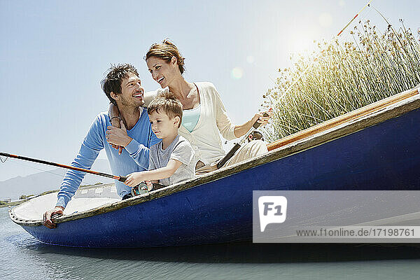 Sohn beim Angeln  während er neben seinen Eltern im Ruderboot sitzt  an einem sonnigen Tag