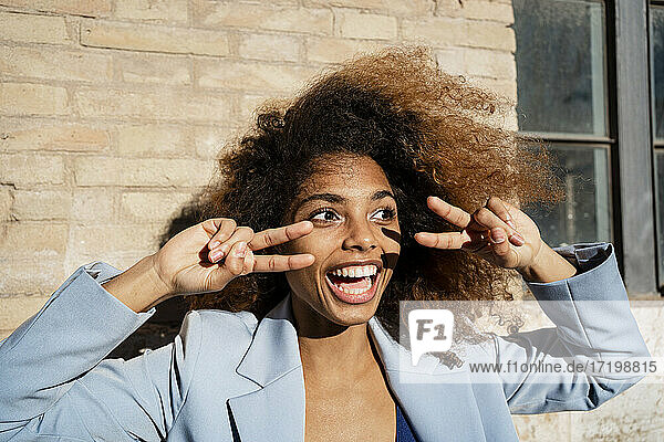 Fröhliche Afro-Frau gestikuliert gegen die Wand