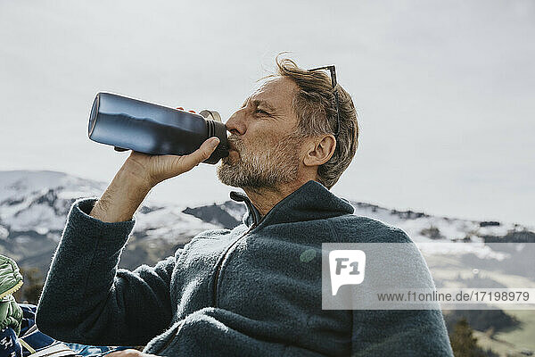 Älterer Mann trinkt Wasser gegen den Himmel im Salzburger Land  Österreich