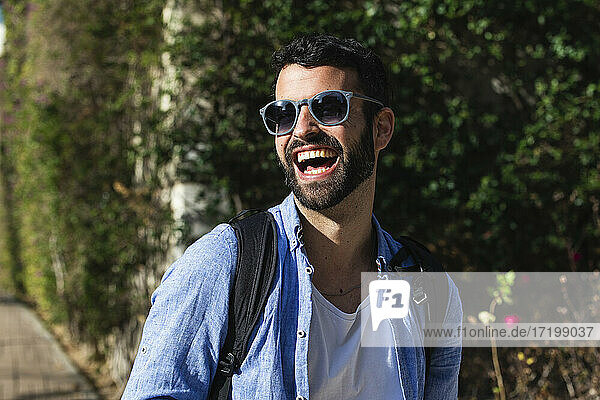 Cheerful male businessman in sunglasses at park
