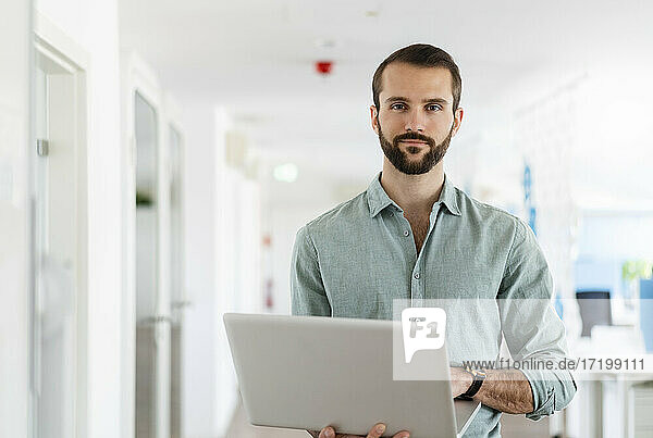 Junger Unternehmer mit Laptop im Büro