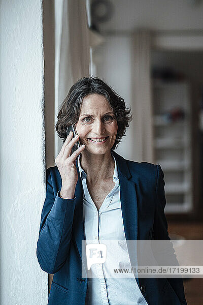Smiling businesswoman talking on smart phone at home