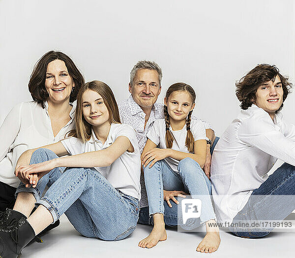 Family with children sitting against white background