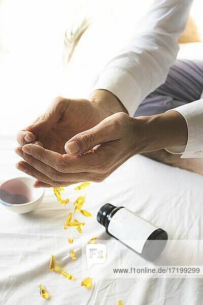 Geschröpfte Hände einer Frau über Vitamintabletten  die auf das Bett fallen