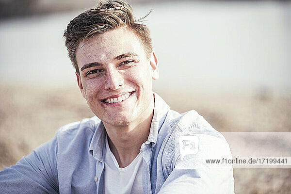 Hübscher junger Mann lächelt an einem sonnigen Tag