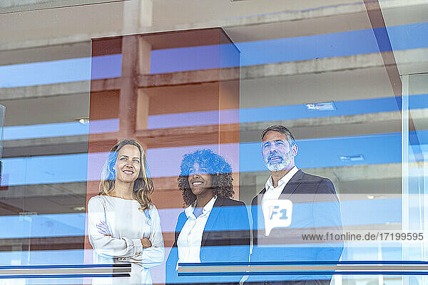 Unternehmer  die lächelnd durch ein Fenster in ein modernes Büro blicken