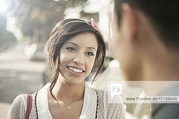 Girlfriend smiling while looking at boyfriend on sunny day