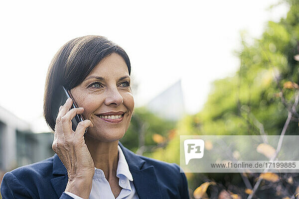 Smiling female entrepreneur talking on mobile phone at office park