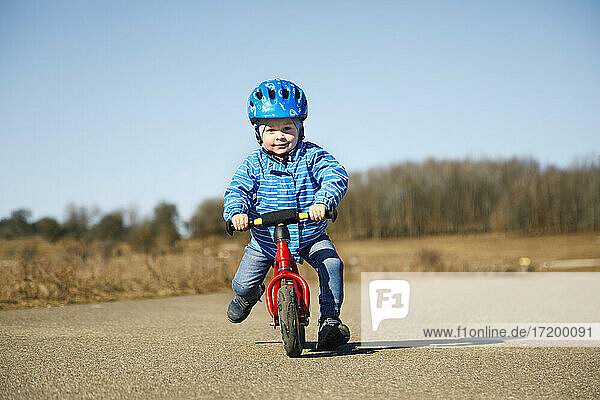 Niedlicher Junge mit Fahrradhelm auf dem Fahrrad an einem sonnigen Tag auf der Straße