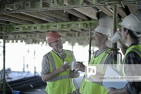 Lächelnde Bauarbeiter  die auf der Baustelle diskutieren