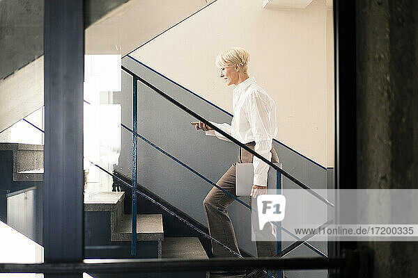 Businesswoman seen through glass wall while moving up on staircase