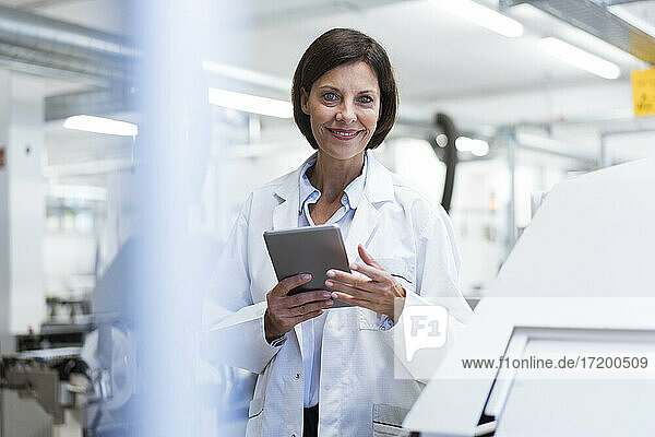 Lächelnde Wissenschaftlerin mit digitalem Tablet im Labor