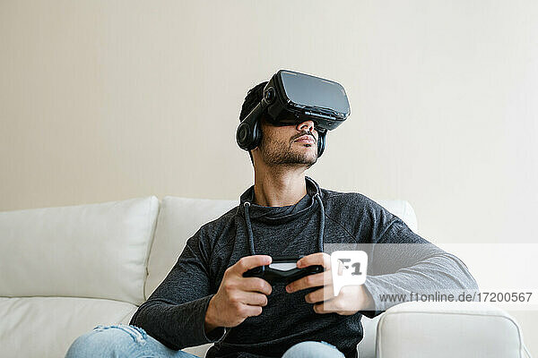 Young man playing video game through virtual reality simulator