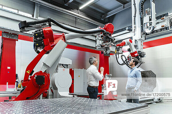 Männliche Unternehmer diskutieren über Robotik in der Fabrik