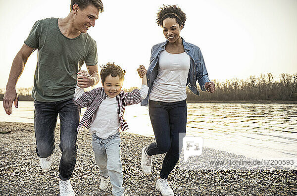 Fröhlich spielend beim Laufen mit Eltern am See