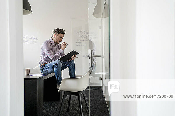 Geschäftsmann beim Brainstorming mit Blick auf das Klemmbrett im Büro