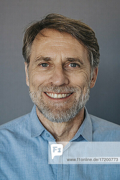 Lächelnder Mann mit Bart vor grauem Hintergrund