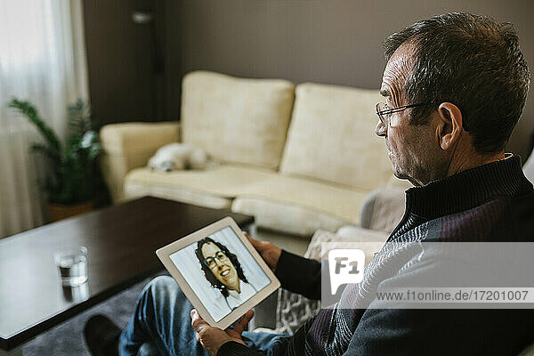 Lächelnde Ärztin bei einer Videokonsultation mit einem älteren männlichen Patienten zu Hause während COVID-19