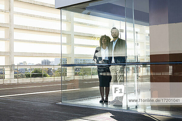 Unternehmer schauen durch ein Fenster  während sie in einem modernen Büro stehen