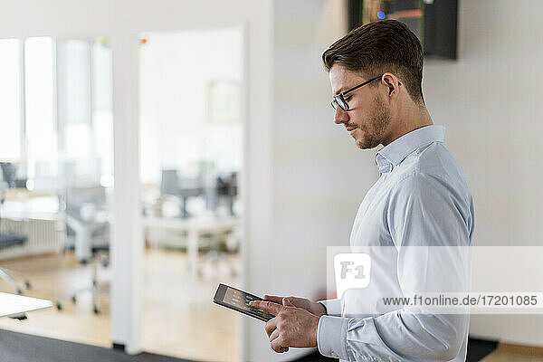 Männlicher Unternehmer  der ein digitales Tablet bei der Arbeit im Büro benutzt