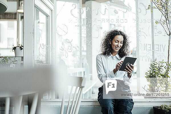 Lächelnde junge Geschäftsfrau  die ein digitales Tablet benutzt  während sie in einem Café sitzt