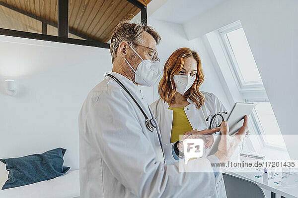 Arzt diskutiert mit einem Kollegen über ein digitales Tablet  während er in der Klinik steht