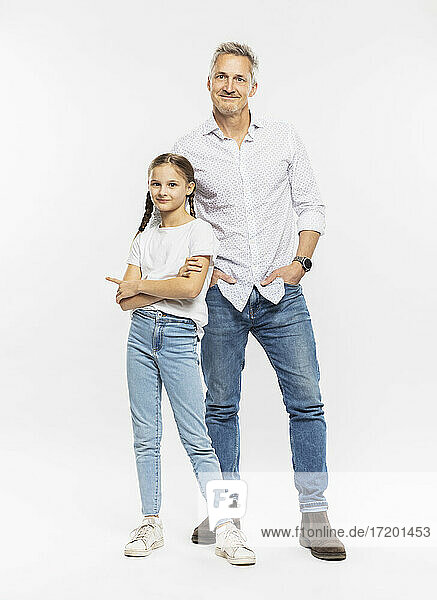 Smiling man standing with daughter against white background