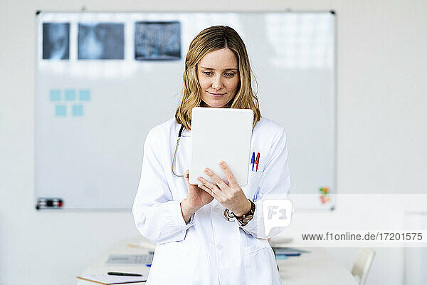 Weibliche medizinische Fachkraft  die zu Hause ein digitales Tablet benutzt