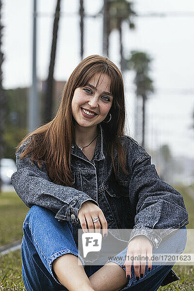 Lächelnde junge Frau auf dem Gleis einer Straßenbahnhaltestelle