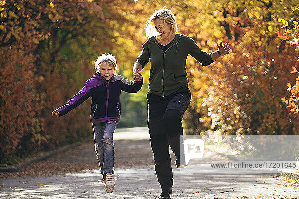 Glückliche Mutter und Tochter laufen im Park im Herbst